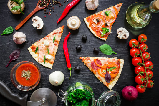 Italian pizza with ingredients and vegetables on dark table. Flat lay, top view. Sliced pizza pattern