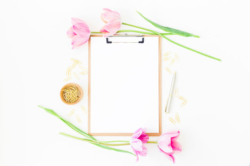 Freelancer or blogger workspace with clipboard, notebook, pink tulips and accessories on white background. Flat lay, top view.