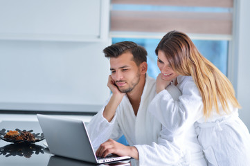 Portrait of a couple in the kitchen and using a laptop