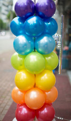 Balloons stacked on a pole on the sidewalk