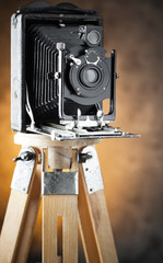 Old camera on a tripod on an old background close-up