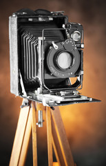 Old camera on a tripod on an old background close-up