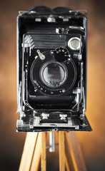 Old camera on a tripod on an old background close-up
