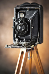 Old camera on a tripod on an old background close-up