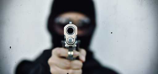 Criminal robber with aiming gun, Bad guy in hood holding pistol handgun. - obrazy, fototapety, plakaty