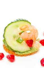 Light and tasty cracker with shrimps on crisp and juicy cucumber slices with cool and creamy avocado on white