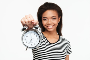 Portrait of a happy african teen girl showing alarm clock