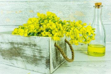Rapeseed flowers with a bottle of rapeseed oil on a rustic wooden table