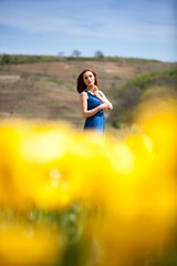Obraz na płótnie Canvas Beautiful woman in blue dress in flower field in sunny summer day. Beautiful girl in springtime