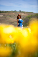 Naklejka na ściany i meble Young beautiful gorgeous woman in flower field in sunny summer day. Beautiful girl in springtime