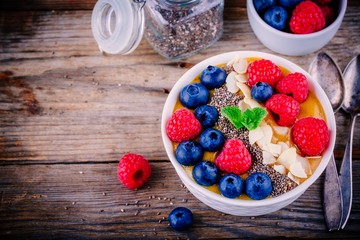 Mango smoothie bowl with raspberries, blueberries, chia seeds and almonds