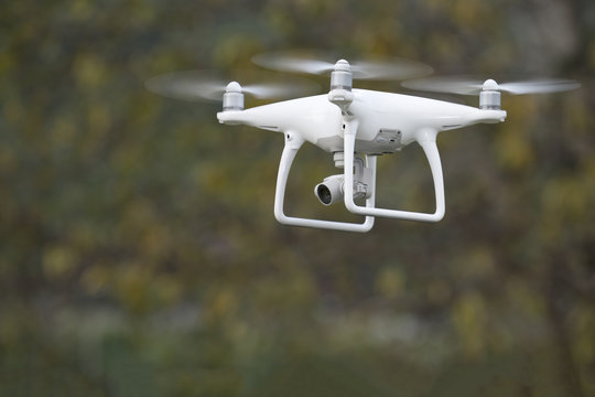 White drone flying with green background.