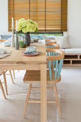 wooden dining table in modern dining room with table set and vase of plants
