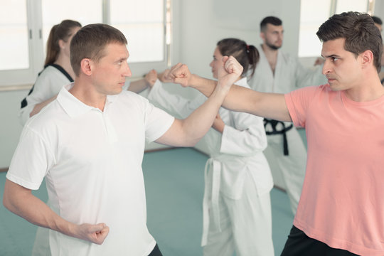 Adult males and females are practicing new karate moves in pairs