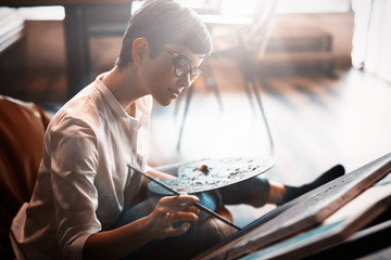 Female artist painting with palette and paintbrush