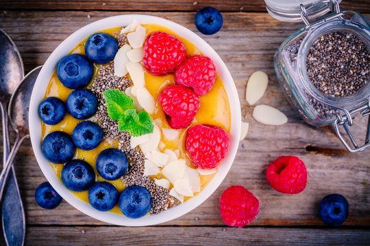 Mango smoothie bowl with raspberries, blueberries, chia seeds and almonds