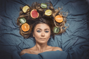 Beautiful gorgeous model girl with colorful citrus healthy fruits in her shiny hair. Care and hair...