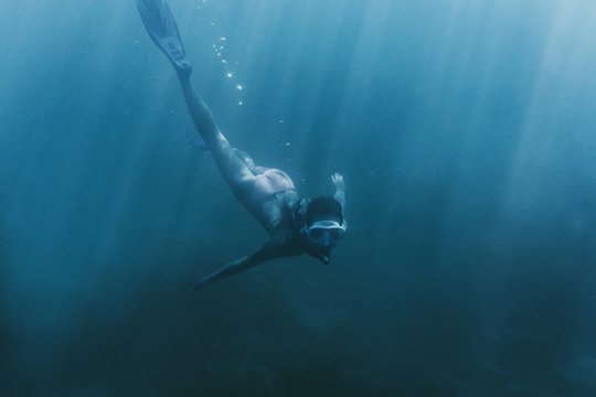Freediver woman swimming in deep sea.