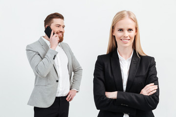 Happy lady standing near her colleague man talking by phone