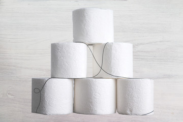 Stack of toilet paper rolls on wooden table against white brick wall. Copy space.