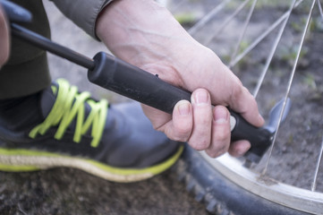 Male inflates bicycle wheel with a pump. Close-up