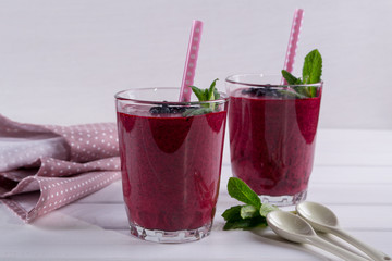 Two glasses of blueberry smoothie on white table