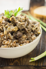 Buckwheat porridge and meat in a white bowl on a wooden table. Healthy dishes. Traditional russian food.