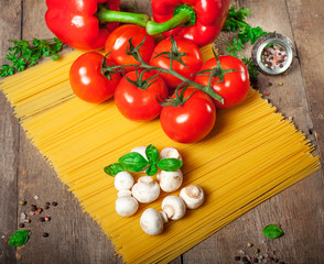 Italian dry pasta spaghetti with tomatoes and fresh herbs on a dark wooden background, selective focus