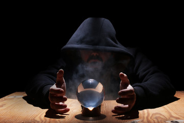 man in a black hood with cristal ball