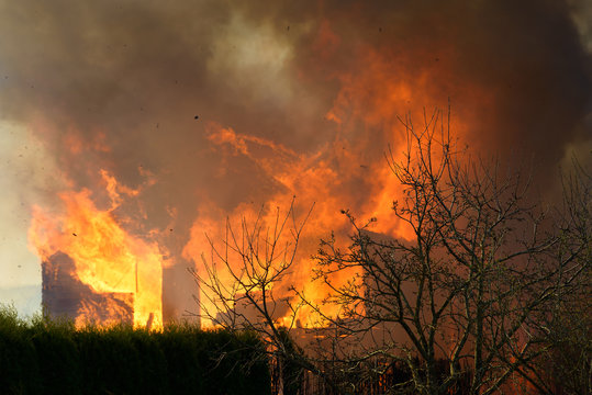 House burning on fire. Building covered by flame. Flaming wooden construction.