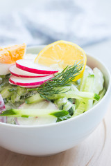 Vegetable salad with yogurt dressing with eggs in a white bowl on wooden board. Various vegetables in a white bowl on wooden board. Healthy summer snack. Clean eating.