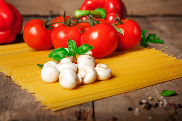 Italian dry pasta spaghetti with tomatoes and fresh herbs on a dark wooden background, selective focus