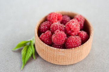 Fresh summer raspberry in a wooden bowl. Selective focus.