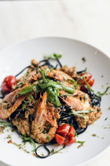 gourmet grilled prawn and vegetables on black squid ink pasta