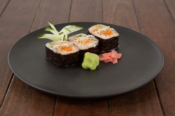 Three maki sushi served in black round plate