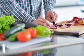 Handsome man cooking at home preparing salad in kitchen.
