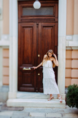 Fototapeta premium Woman in white dress in front of huge brown wooden door
