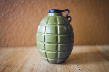 green grenade resting on wooden table on blurry background.