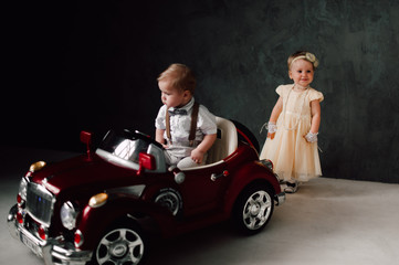 Plakat two babies wedding - boy and girl dressed as bride and groom playing with toy car