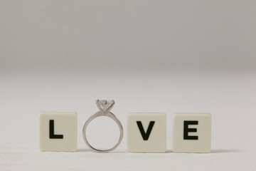 Diamond ring between white blocks displaying love message