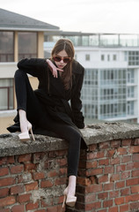 Cute woman sitting on red brick fence