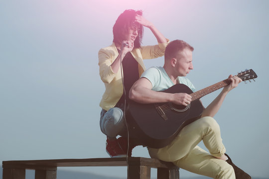 Cute girl singing and handsome man playing guitar on table