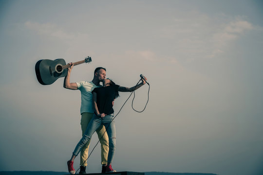 Romantic couple of musicians kissing on idyllic, blue sky