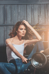 Naklejka na ściany i meble girl biker sitting on vintage motorcycle in garage
