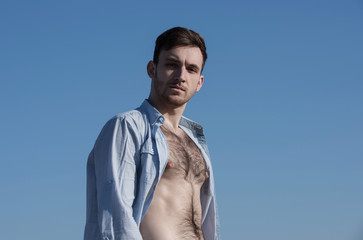 Handsome man posing in unbutton shirt with hairy, naked torso
