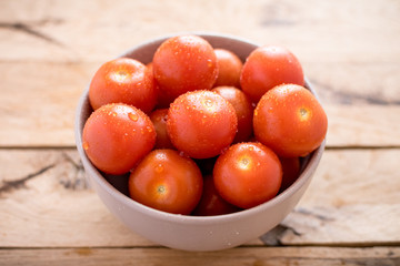 fresh cherry tomatoes in bowl on wooden background.