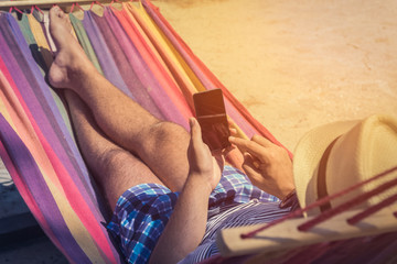 Man using smartphone in hammock 