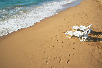 Fototapeta na wymiar two loungers on the beach near the shore