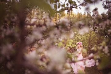 A young girl in floral wreath in nature