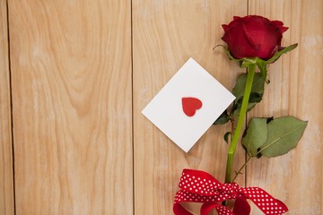 Red rose wrapped in ribbon and heart printed envelope